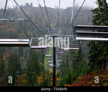 Seggiovia sulla cima di una montagna coperta di alberi durante la offseason di una stazione sciistica Foto Stock