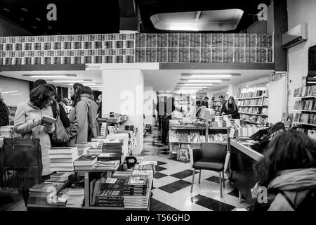 Athens, Grecia - 26 Mar 2016: vista dalla strada all'interno di book store libreria con i clienti dello shopping di libri di notte - bella donna greca alla ricerca di nuovi libri da leggere Foto Stock