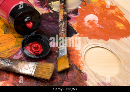 Artista spazzole, vernice rossa e tubo orizzontale della tavolozza Foto Stock