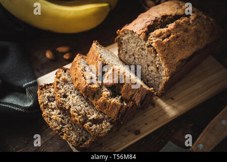 In casa pane alla banana o torta di pane affettato su legno. Morbida luce mattutina, scuro moody cibo fotografia. Primo piano Foto Stock