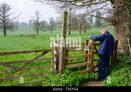 Un uomo passa attraverso un bacio porta a piedi lungo un sentiero pubblico attraverso campi verdi al di là attraverso il Shropshire campagna vicino Worfield. Foto Stock