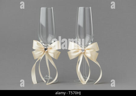 Matrimonio di due bicchieri di vino decorate con nastri di color crema. Foto Stock