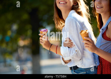 Immagine ravvicinata di coni gelato nelle mani di una donna in piedi con il suo amico. Due giovani donne all'aperto di mangiare gelato in una giornata di sole. Vista isolata, Foto Stock