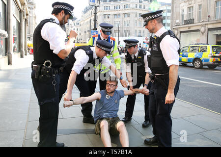 Un attivista ambientale è visto di essere arrestato dai poliziotti presso la Oxford Circus durante il quinto giorno del cambiamento climatico protesta da parte di la ribellione di estinzione Gruppo movimento Un grande numero di presenza della polizia intorno al rosa yacht come essi ONU-bond gli attivisti che incollati stessi e la polizia si prepara a rimuoverli dal sito. Secondo la polizia si è riunito, oltre mille militanti sono stati arrestati poiché la dimostrazione è iniziato il 11 aprile 2019. Foto Stock