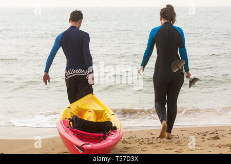 Bournemouth Dorset, Regno Unito. 22 apr, 2019. Regno Unito meteo: dopo un inizio nebuloso il glorioso meteo continua con caldo e soleggiato, come testa beachgoers al mare per godere del calore e del sole a Bournemouth spiagge del Lunedì di Pasqua prima che i cambiamenti climatici e il ritorno al lavoro. Paio di andare in kayak - giovane a piedi in mare con il kayak. Credito: Carolyn Jenkins/Alamy Live News Foto Stock