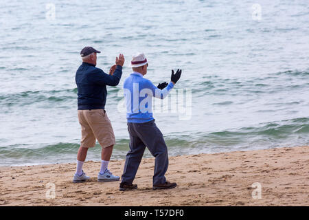 Bournemouth Dorset, Regno Unito. 22 apr, 2019. Regno Unito meteo: dopo un inizio nebuloso il glorioso meteo continua con caldo e soleggiato, come testa beachgoers al mare per godere del calore e del sole a Bournemouth spiagge del Lunedì di Pasqua prima che i cambiamenti climatici e il ritorno al lavoro. La mattina presto esercizi sulla riva del mare - due vecchi vecchi uomini anziani facendo tai chi esercita all'aperto sulla spiaggia. Credito: Carolyn Jenkins/Alamy Live News Foto Stock