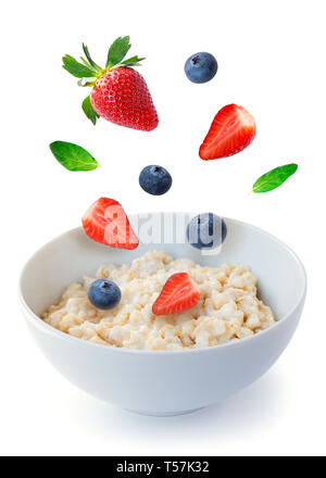 Fragole e mirtilli sono battenti in un recipiente con i fiocchi d'avena. Una sana prima colazione. Isolato su sfondo bianco. Foto Stock