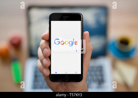 Un uomo guarda al suo iPhone che visualizza il logo di Google (solo uso editoriale). Foto Stock