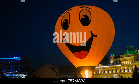 In mongolfiera ad aria calda con giallo Smiley face di notte festival Foto Stock