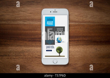 Un iPhone che mostra la Amundi Asset Management sito poggia su una semplice tavola di legno (solo uso editoriale). Foto Stock