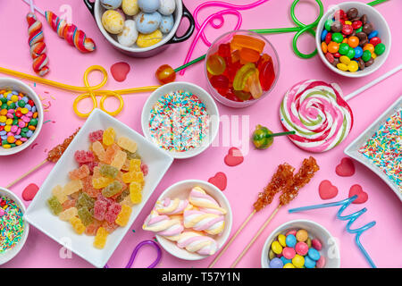 Caramelle assortimento su rosa colore di sfondo, vista dall'alto. Kids festa di compleanno concetto Foto Stock