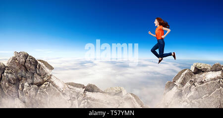 Redhead donna passa attraverso lo spazio tra le colline sulla scogliera sul cielo blu sullo sfondo. Foto Stock