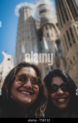 Barcellona Spagna. Il 13 aprile 2019. Origine indiana di donne in occhiali da sole pongono contro lo sfondo delle torri della Sagrada Familia e il blu del cielo di Barcellona. Foto Stock