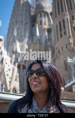 Barcellona Spagna. Il 13 aprile 2019. Origine indiana di donne in occhiali da sole pongono contro lo sfondo delle torri della Sagrada Familia e il blu del cielo di Barcellona. Foto Stock