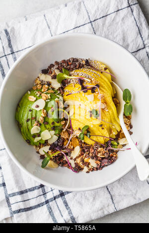 Muesli con avocado, superfoods bacche e frutti in una ciotola bianco. Impianto basato dieta concetto. Foto Stock