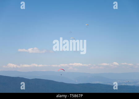 Gli uomini in volo in parapendio nel cielo blu in una giornata di sole Foto Stock