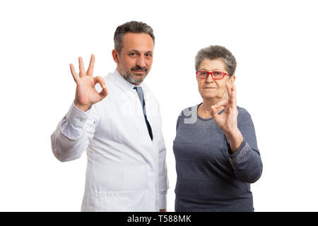 Gentile medic uomo e paziente anziano donna che indossa occhiali o occhiali di protezione rendendo okay gesto con le dita isolato su bianco di sfondo per studio Foto Stock