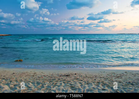 Immagine di splendida Landa spiaggia di Agia Napa, Cipro. Giallo sabbia e contro blu acqua calma con piccole onde in una serata calda in autunno, rosa e w Foto Stock