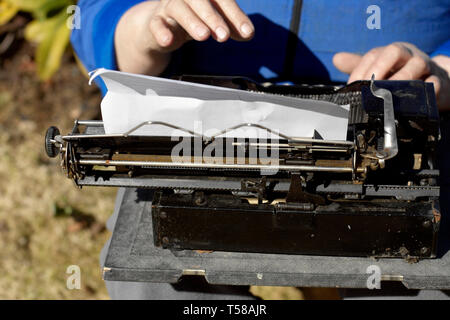 Close-up di mani umane lavorando su vintage manuale dattiloscritto, outdoor shot Foto Stock