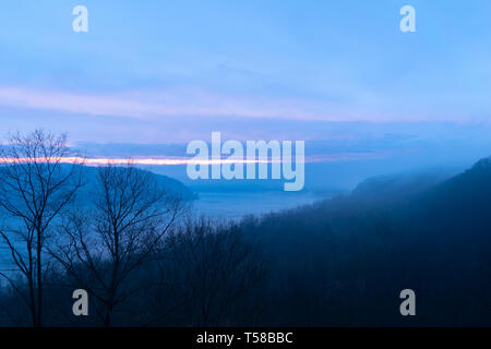 Misty e moody colpo di un ansa del fiume Susquehanna mentre un nastro di tramonto rompe attraverso le dense nubi, Lancaster County, Pennsylvania, PA Foto Stock