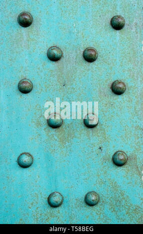 Rivetti di acciaio che tiene insieme un vecchio weathered trave in acciaio con vernice di color turchese Foto Stock