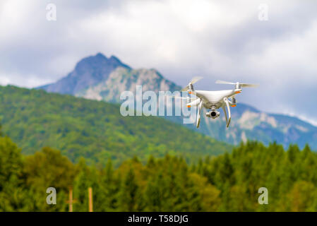 White drone quad copter con alta risoluzione Telecamera digitale volare nel cielo blu sopra la montagna Foto Stock