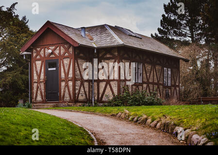 Il cottage, una piccola casa sulla collina circondata dal verde, una terra rossa del sentiero conduce all'ingresso Foto Stock