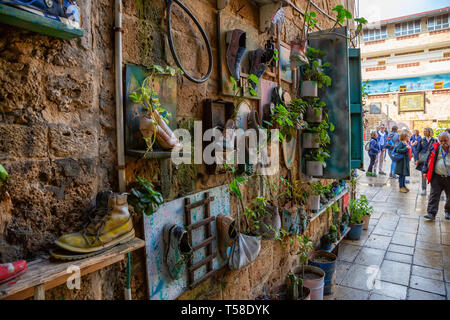 Acre, distretto del Nord, Israele - Aprile 1, 2019: scarpe e le piante sono appesi al muro di mattoni nella città vecchia di Akko. Foto Stock