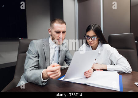 Lavoratore di sesso femminile che mostra le carte per il suo boss gravi nella sala riunioni Foto Stock
