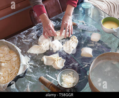 Mani femminili stendete la pasta su un tavolo in vetro per preparare una torta di ricotta. Foto Stock