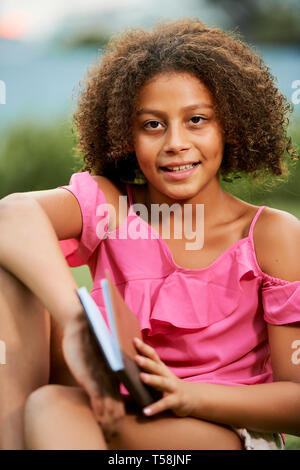 Bella ragazza adolescente libro lettura in posizione di parcheggio Foto Stock