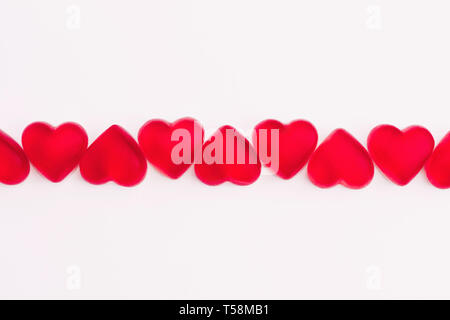 Cuore rosso a forma di caramelle gommose in fila su sfondo bianco. Copia dello spazio. Foto Stock