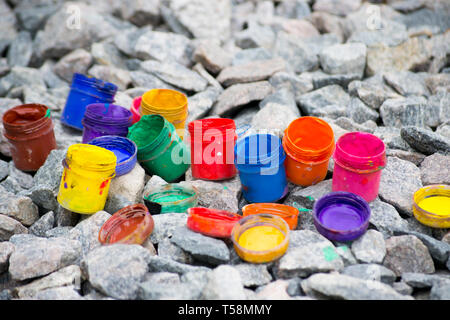 Colorato piccoli barattoli di vernice può giacere su un ciottolo grigio close-up Foto Stock