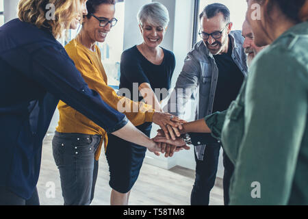 La gente di affari pila le mani insieme. Multi-etnico gruppo di professionisti di mettere le loro mani insieme come un simbolo del lavoro di squadra. Foto Stock
