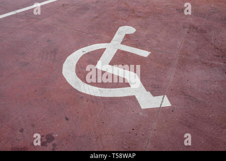 Disabili segno bianco dipinta su un pavimento rosso Foto Stock