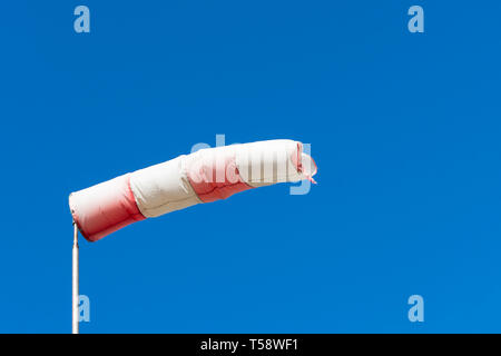 Rosso Bianco manica a vento indica da dove il vento arriva con uno sfondo blu Foto Stock