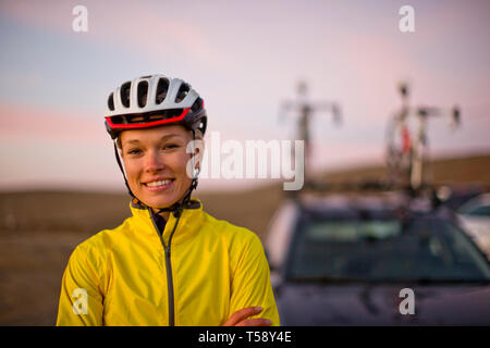 Ritratto di un sorridente giovane donna che indossa un casco in bicicletta. Foto Stock