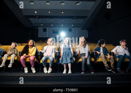 Gruppo di amici multiculturale seduto in prima fila nel cinema Foto Stock
