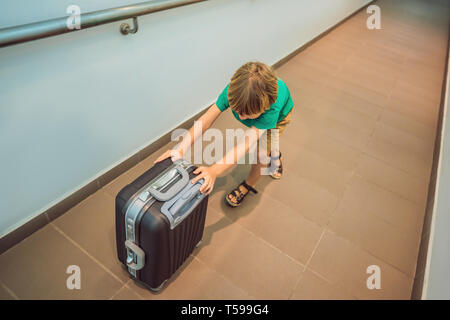 Funny little boy andando su vacanze viaggio con la valigia in aeroporto, in interni Foto Stock