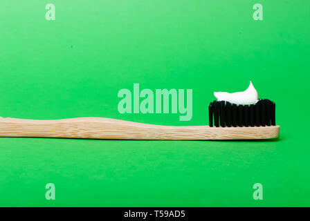 Vicino la vista laterale della testa di spazzolino da denti di bambù su sfondo verde con spazio di copia Foto Stock