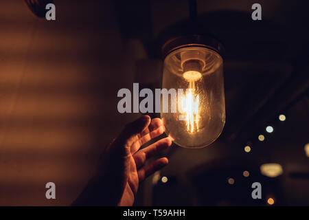 La mano di raggiungere per un vintage lampadina. Foto Stock