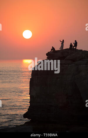 La gente che prende le immagini e seduto sulla sommità della famosa attrazione turistica di pulpito Rock sulla punta di Portland Bill sulla isola di Portland come s Foto Stock