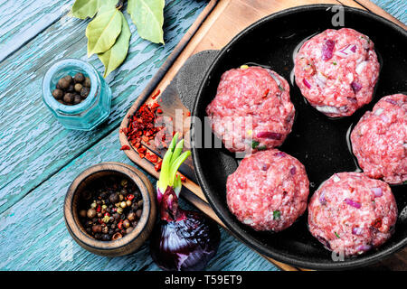 Polpettine di carne di manzo crudo forza-carni in ghisa pan Foto Stock