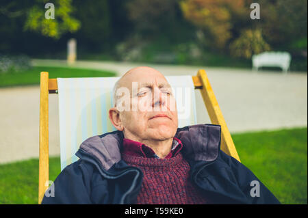 Un uomo anziano è rilassante in una sedia a sdraio all'aperto Foto Stock