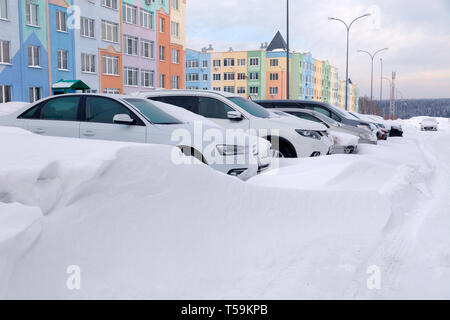 La Russia Kemerovo 2019-01-07 Сar neve al coperto si trova in parcheggio edificio residenziale in inverno. Сoncept maltempo, nevicata, maltempo condi Foto Stock