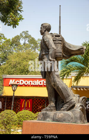 La città di Ho Chi Minh, Vietnam - Marzo 15, 2019 : Statua del Viet Cong soldati rivoluzionario al di fuori Ufficio Generale delle Poste accanto al segno per primo McDonald' Foto Stock