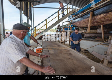 I lavoratori del cantiere navale in cui i tradizionali fiume Tago barche sono costruiti e riparati in Sarilhos Pequenos village a Moita comune, Portogallo Foto Stock