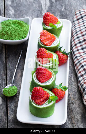 Tè verde Matcha crêpe con la panna montata e fragola sul tavolo di legno Foto Stock