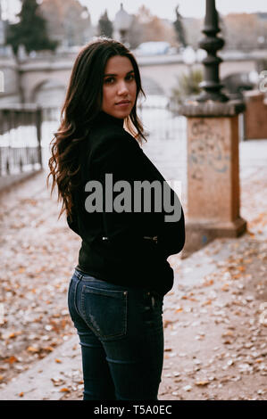 Retroilluminato bella donna ispanica nella parte anteriore del ponte in inverno Foto Stock