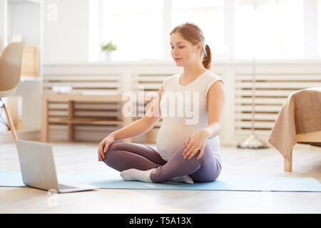 Donna incinta pratica di meditazione Home Foto Stock